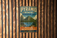 A vintage metal sign for the Pyramid State Recreation Area in Illinois, featuring a mountain landscape and a lake.