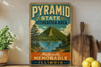 A vintage-style metal sign for the Pyramid State Recreation Area in Illinois, featuring a scenic mountain landscape with a lake and pine trees.