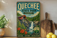 A vintage-style sign for Quechee State Park in Vermont, featuring a red wooden bridge over a waterfall surrounded by lush greenery and flowers.