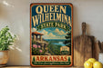 A vintage-style sign for Queen Wilhelmina State Park in Arkansas, featuring a scenic landscape with a cabin and mountains in the background.