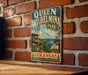 A vintage-style metal sign for Queen Wilhelmina State Park in Arkansas, featuring a scenic landscape with a cliff, river, and mountains.