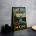 A vintage-style metal sign for Range Ponds State Park in Maine, featuring a scenic image of a lake with a red canoe and pine trees.