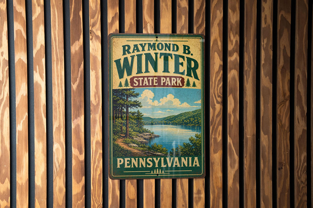 A vintage-style metal sign for Raymond B. Winter State Park in Pennsylvania, featuring a scenic landscape with a lake and mountains.