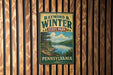 A vintage-style metal sign for Raymond B. Winter State Park in Pennsylvania, featuring a scenic landscape with a lake and mountains.
