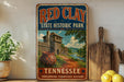 A vintage-style sign for Red Clay State Historic Park in Tennessee, featuring a rustic image of a log cabin and a dirt path.