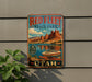 A vintage-style metal sign for Red Fleet State Park in Utah, featuring a scenic image of a boat on a lake surrounded by mountains.