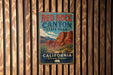 A vintage metal sign for Red Rock Canyon State Park in California, featuring a scenic illustration of the canyon landscape.