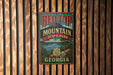 A vintage metal sign for Red Top Mountain State Park in Georgia, featuring a scenic landscape with a lake and mountains.