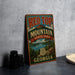 A vintage-style metal sign for Red Top Mountain State Park in Georgia, featuring a scenic landscape with a mountain, lake, and trees.