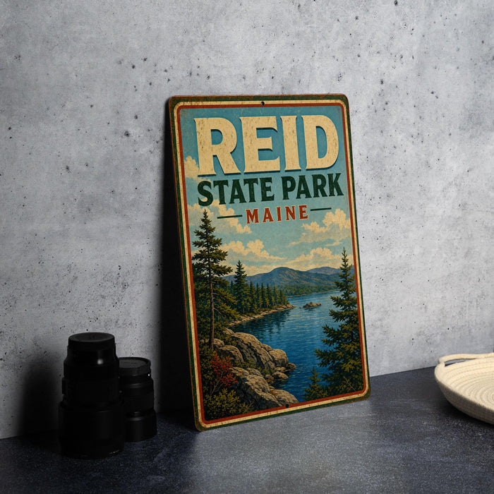 A vintage-style sign for Reid State Park in Maine, featuring a scenic landscape with pine trees, a lake, and mountains.