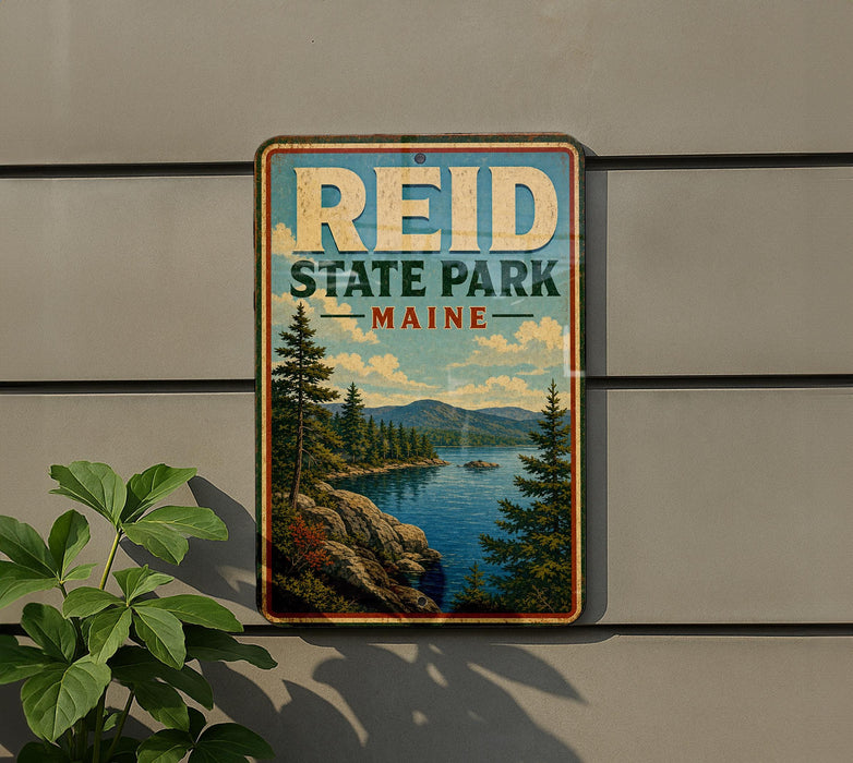 A metal sign with the text "REID STATE PARK MAINE" is displayed on a wall, featuring a scenic landscape with pine trees, a lake, and mountains.