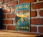 A vintage-style sign for the Rend Lake State Fish & Wildlife Area in Illinois, featuring illustrations of fish and wildlife.