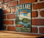 A vintage-style metal sign for Rice Lake State Park in Minnesota, featuring a scenic illustration of a lake, canoe, and forest.