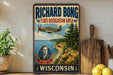 A vintage-style sign for the Richard Bong State Recreation Area in Wisconsin, featuring a vintage airplane and a portrait of a man.