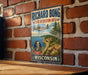 A vintage-style metal sign for Richard Bong's State Recreation Area in Wisconsin, featuring a plane flying over a scenic landscape.