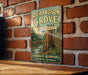 A vintage-style metal sign for Richardson Grove State Park in California, featuring a scenic illustration of a forest with a bridge and a river.