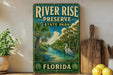 A vintage-style sign for River Rise Preserve State Park in Florida, featuring a serene landscape with palm trees, a heron, and a river.