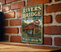 A vintage-style metal sign for the Rivers Bridge, a historic site in South Carolina, is displayed on a brick wall.