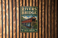 A vintage-style metal sign for the Rivers Bridge, a historic site in South Carolina, is displayed on a wooden wall.