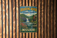 A vintage metal sign for Roaring River State Park in Missouri, featuring a waterfall and a red brick building.