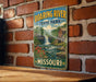 A vintage-style sign for Roaring River State Park in Missouri, featuring a scenic image of a waterfall and a mill.