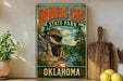 A vintage-style sign for Robbers Cave State Park in Oklahoma, featuring a scenic image of the cave and surrounding landscape.