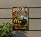 A vintage-style metal sign for Rock Creek Station, a State Historical Park in Nebraska, featuring a train and a yellow building.