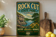 A vintage-style metal sign for Rock Cut State Park in Illinois, featuring a scenic landscape with a river, cliffs, and flowers.