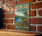 A vintage-style metal sign for Rocky Gap State Park in Maryland, featuring a scenic landscape with mountains, a lake, and a pine tree.
