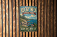 A vintage-style metal sign for Rocky Neck State Park in Connecticut, featuring a scenic landscape with a rocky coastline, a lake, and a sailboat.