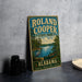 A vintage-style metal sign for Roland Cooper State Park in Alabama, featuring a scenic landscape with a lake, trees, and a bird.