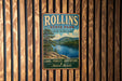 A vintage metal sign for Rollins State Park in New Hampshire, featuring a scenic image of a lake surrounded by pine trees and mountains.