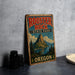 A vintage-style sign for Rooster Rock State Park in Oregon, featuring a mountain landscape and text.