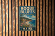 A vintage metal sign for Roque Bluffs State Park in Maine, featuring a scenic landscape with a beach, mountains, and a pine tree.