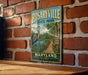 A vintage metal sign for Rosaryville State Park in Maryland, featuring a scenic illustration of a wooden bridge, a heron, and a body of water.