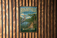 A metal sign for Rosaryville State Park in Maryland, featuring a scenic illustration of a bird and a wooden walkway leading to a lake.