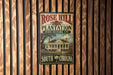 A vintage-style metal sign for Rose Hill Plantation, a historic site in South Carolina, is displayed on a wooden wall.