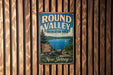 A vintage metal sign for the Round Valley Recreation Area in New Jersey, featuring a scenic image of a lake and mountains.