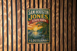 A vintage metal sign for Sam Houston Jones State Park in Louisiana, featuring a scenic illustration of a lake, palm trees, and a bird.