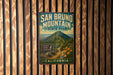 A vintage metal sign for San Bruno Mountain State Park in California, featuring a scenic mountain landscape with a trail leading to a wildlife viewing area.