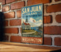 A vintage-style metal sign for San Juan Island National Historical Park in Washington, featuring a lighthouse and a scenic landscape.