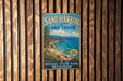 A vintage-style metal sign for Sand Harbor at Lake Tahoe, Nevada, featuring a scenic image of the lake and mountains.