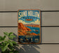 A vintage-style metal sign for Sand Hollow State Park in Utah, featuring a scenic illustration of the park's landscape and water.
