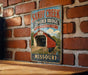 A vintage-style metal sign for the Sandy Creek Covered Bridge in Missouri, featuring an illustration of the bridge and the surrounding landscape.