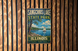 A vintage metal sign for Sangchris Lake State Park in Illinois, featuring a sailboat on a lake and a scenic landscape.