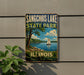 A vintage-style sign for Sangchris Lake State Park in Illinois, featuring a sailboat on the lake and a scenic landscape.