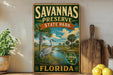 A vintage-style sign for Savannas Preserve State Park in Florida, featuring a bird and palm trees in a tropical landscape.
