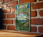 A vintage metal sign for Savoy Mountain State Forest in Massachusetts, featuring a scenic illustration of a forest and a lake.