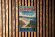 A vintage metal sign for Scarborough State Beach in Rhode Island, featuring a beach scene with a wooden fence and ocean waves.
