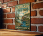 A vintage-style metal sign for Schoolcraft State Park in Minnesota, featuring a scenic landscape with pine trees, a lake, and mountains.